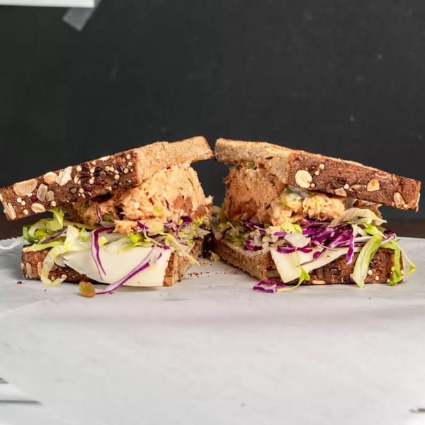 Two halves of a healthy tuna salad sandwich on seeded whole-grain bread with lettuce, red cabbage, and cheese.