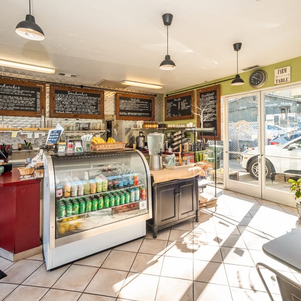 Interior of The Healthy Habit, a bright, clean cafe with menu boards, a display fridge, and outdoor light.