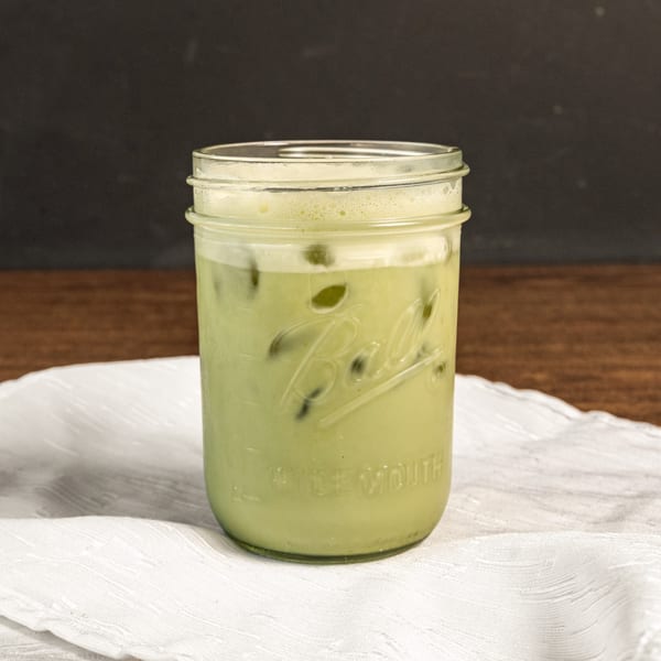 A healthy green iced matcha latte in a mason jar on a white napkin.