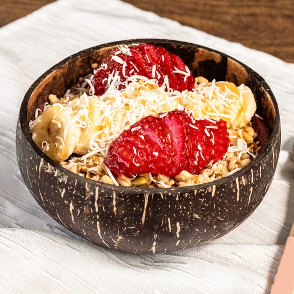 A healthy breakfast bowl with granola, strawberries, bananas, and shredded coconut in a coconut shell.